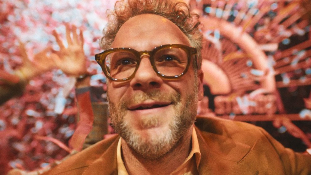 Seth Rogen as Matt Remick in "The Studio," smiling in front of red lights in the background